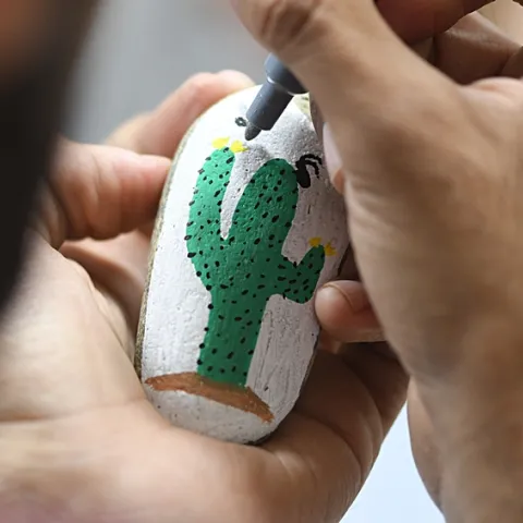 Entomologist Joel Hernandez adds the finishing touches on a rock painted by his wife, Melissa Cruz, the outreach coordinator for the UC Davis Arboretum and Public Garden. (Photo by Kathy Keatley Garvey)