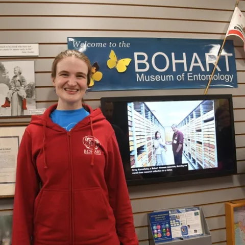 Entomologist/artist Charlotte Herbert Alberts wearing a red hooded sweatshirt: front view showing the Bohart logo and a tardigrade face. (Photo by Kathy Keatley Garvey)