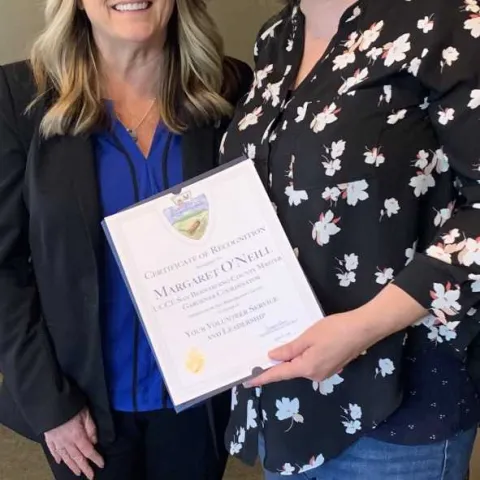 Maggie receiving recognition from Supervisor Rowe's Chief of Staff Gayle Covey