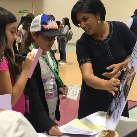 During the career fair, an Engineer speaks with youth about what she does for her job