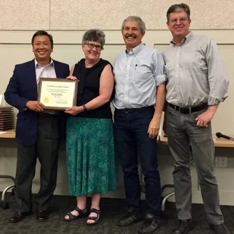 Jan Corlett, second from left, receives thanks and congratulations from Tu Tran, Mark Bell and John Fox.