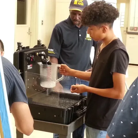 Dr.Peter Ako Larbi guides a student in measuring nozzle output volume per time, as affected by pressure.