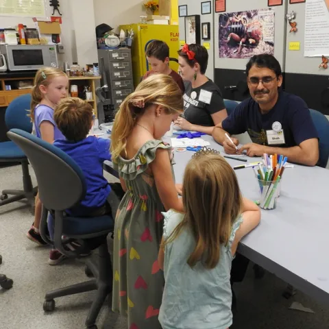 Visiting scholar Syed Fahad Shah and doctoral student Charlotte Herbert Alberts (next to him) help youngsters make buttons at the Bohart Museum of Entomology open house. (Photo by Kathy Keatley Garvey)