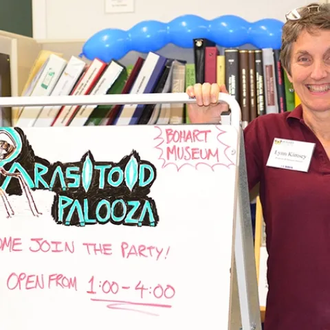 Lynn Kimsey, director of the Bohart Museum of Entomology, stands by a Parasitoid Palooza sign. (Photo by Kathy Keatley Garvey)