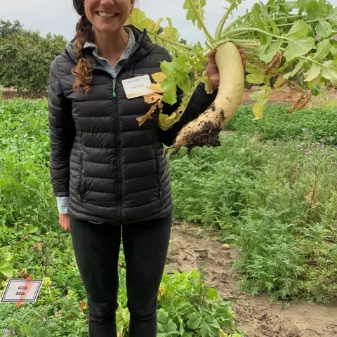 Alli holding a daikon radish.