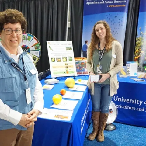 Lindcove REC director Beth Grafton-Cardwell, left, and staff research associate Stephanie Doria hand out citrus at the UC ANR booth at World Ag Expo.