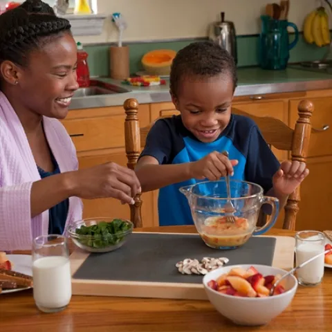 A caregiver and child beating eggs in the kichent - photo SDA's Food and Nutrition Service (FNS), Supplemental Nutrition Assistance Program.