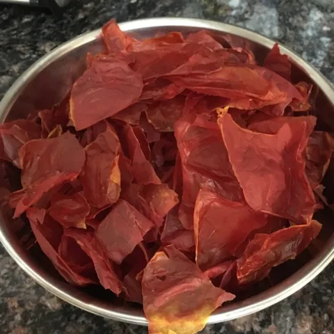 Dried tomato skins in a bowl - dry them plain (as pictured) or add spices before drying. Eat as a snack or grind into a powder.