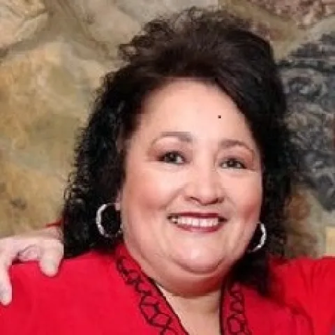 Profile image of Edna Blackhurst, she has black hair and is wearing a red blouse.