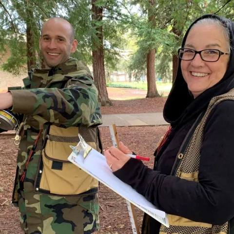Two participants smile at the camera during a workshop in a forest.