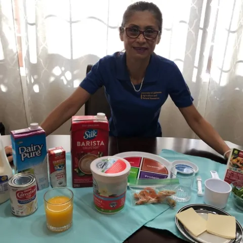 EFNEP educator Nelly Camacho standing at healthy food demonstration table.