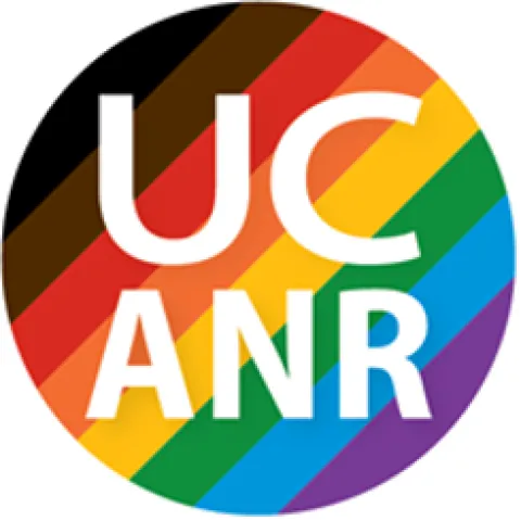 Circle containing the letters UC ANR on a background of rainbow-colored stripes.