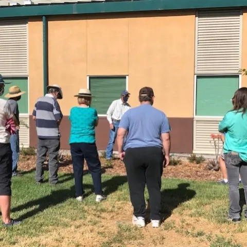 Six people facing an instructor giving a lesson about trees.