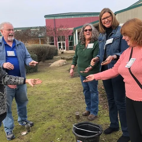 Five smiling gardeners with hands full of soil.