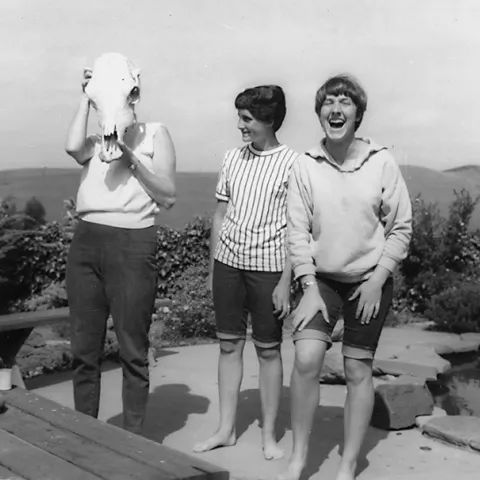 Lynn Siri (far right), now UC Davis professor Lynn Kimsey, laughs with her sister, Anne, as their mother, Jean Siri, tries on a skull.