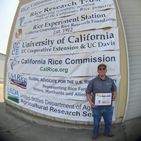 Aaron Alvarez, UC Davis graduate student, accepts D. Marlin Brandon Rice Research Fellowship award during the California Rice Field Day 2021.