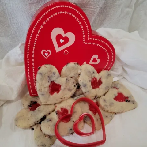Red heart in the background. Heart shaped cookies on a white table cloth