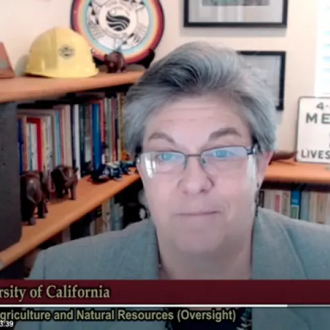 Glenda Humiston speaks onscreen. A plaque on the bookshelf behind her reads, "4-H club member lives here."