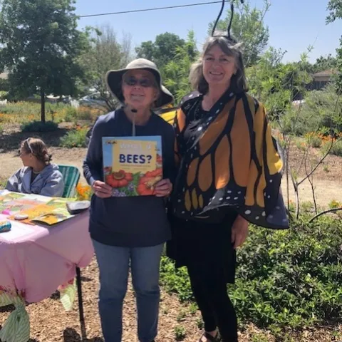 Denise is holding a book about bees, and Rhonda is dressed like a monarch butterfly.