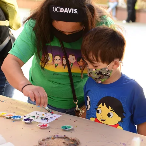 UC Davis alumnus Angie Velazquez of Los Angeles assists her son, Hudson Carr, 4, in his first Maggot Art project. (Photo by Kathy Keatley Garvey)
