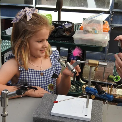Ella Eich proudly displays the pink fly created by Paul Berliner of the Fly Fishers of Davis. (Photo by Kathy Keatley Garvey)