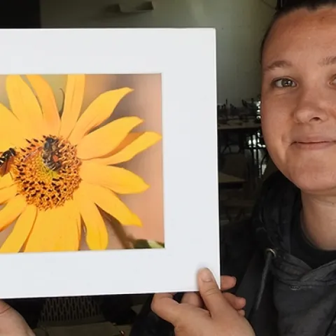 Marine biologist Leta Myers, who clerked at the Dixon May Fair judging, holds a photo by Vaca Valley 4-H'er Matthew Agbayani. It depicts a honey bee and a syrphid fly on a sunflower. (Photo by Kathy Keatley Garvey)