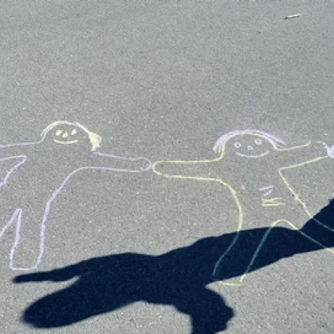 A girl plays among chalk figures drawn on pavement.