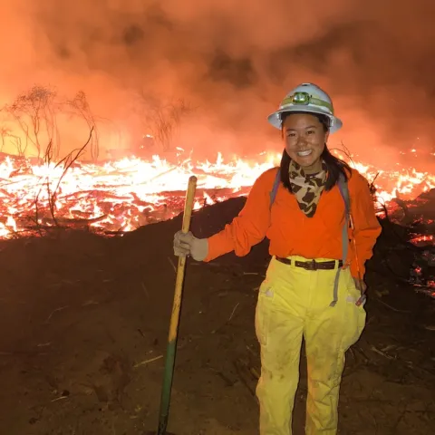 Katie Low standing in front of a prescribed fire