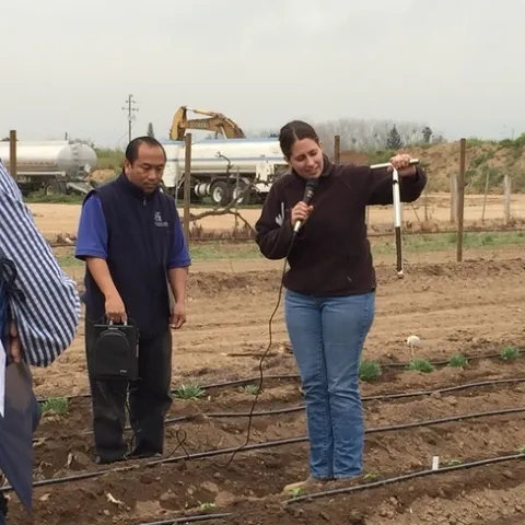 Pie de grabado “Este proyecto expandirá nuestros esfuerzos actuales para apoyar a los agricultores a pequeña escala para que tengan acceso a equipo, mercados nuevos y apoyo técnico”, mencionó Ruth Dahlquist-Willard, quien fue captada demostrando cómo evaluar la humedad de la tierra junto con Michael Yang. Fotografía por Ka Xiong