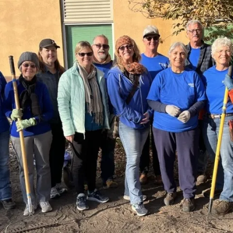 Group of 11 Master Gardeners holding tools and smiling.