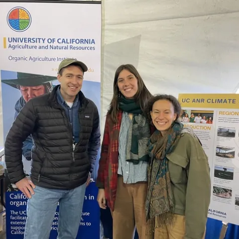 OAI representatives stand in front of posters about the Organic Agriculture Institute and climate-smart agriculture