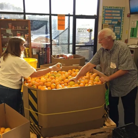 Two food bank volunteers sort oranges.