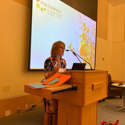 Beth speaking at a lectern. Slide behind her reads "Postharvest Center."
