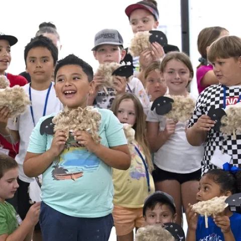 Kids hold up their paper sheep, crafted from freshly sheared wool