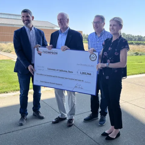 Four people hold a large ceremonial check for $1,205,966.