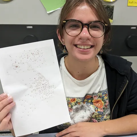 Hanna Briggs, a UC Davis transfer student, holds a sample card showing how glitter mimics insects. She is an intern in the laboratory of arachnologist Jason Bond, the Schlinger Endowed Chair, UC Davis Department of Entomology and Nematology, and associate dean, College of Agricultural and Environmental Sciences.