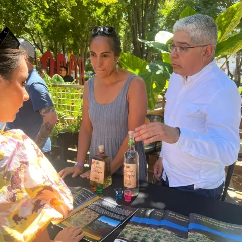 Paulina Rojas, PhD student in the UC Davis Ecology Graduate Group and research project leader Samuel Sandoval Solis, UC Cooperative Expension specialist in water resources managment offering pulque tasting to an event attendee.