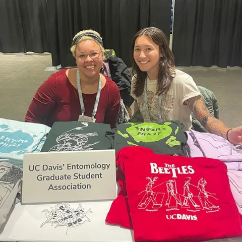 UC Davis doctoral students Iris Quayle (left) of the Jason Bond lab and Mia Lippey of the labs of UC Davis distinguished professor Jay Rosenheim and assistant professor Emily Meineke, show some of the EGSA T-shirts. Lippey serves as EGSA president, and Quayle as treasurer.