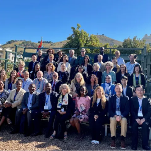 About 40 people sit in bleachers outdoors for a group photo.