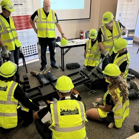 Participants in emergency preparedness training practice using a pry bar to move an object off of a person