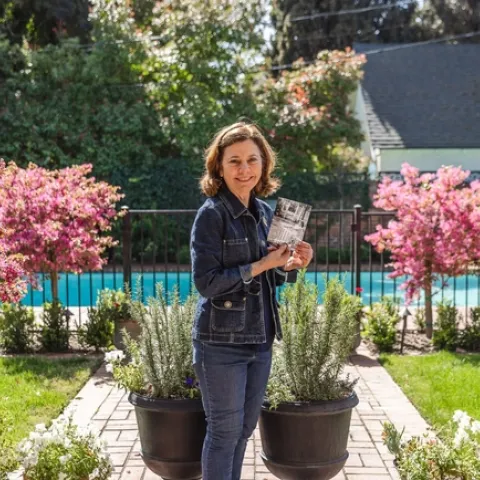 Barbara Vartan holds a photo of herself as a toddler enjoying the backyard at what is now the Clark/Kendrick home. (Photo: Sarah del Pozo)
