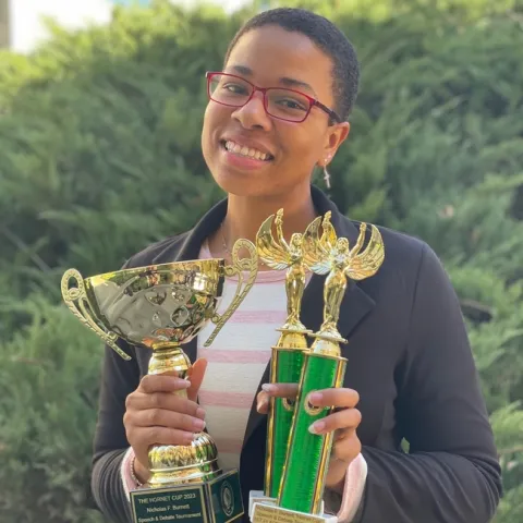 Youth holding 3 trophies in her hands