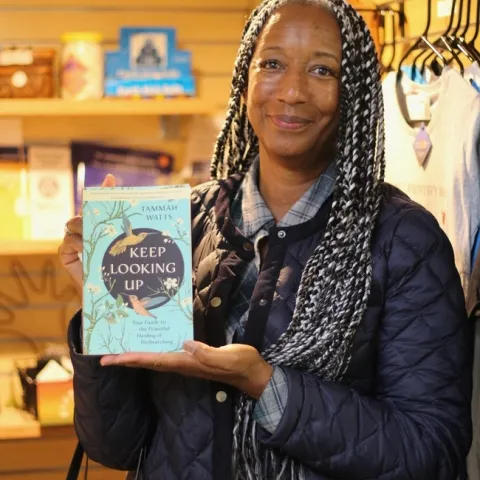 Tammah Watts posa con su libro Keep Looking Up: A Guide to the Powerful Healing of Birdwatching (Sigue mirando hacia arriba: una guía para la poderosa sanación con la observación de aves). Todas las fotografías por Saoimanu Sope.