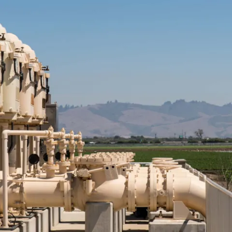 Metal pipe structure is next to a farm field