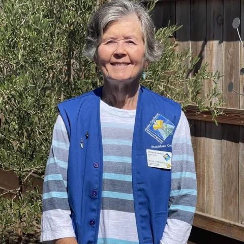 Smiling woman wearing blue vest.