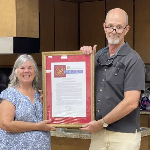 Gerry and Franz stand holding opposite sides of the large, framed document.