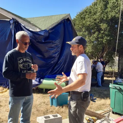 Lewis and Sutherland stand in front of a tarped structure