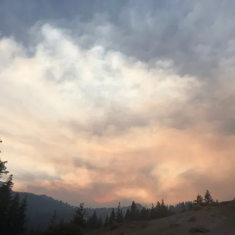 Smoke fills the air above forested mountains
