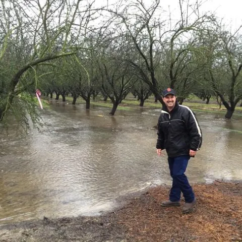 Roger smiles as he stands in a flooded dormant almond orchard