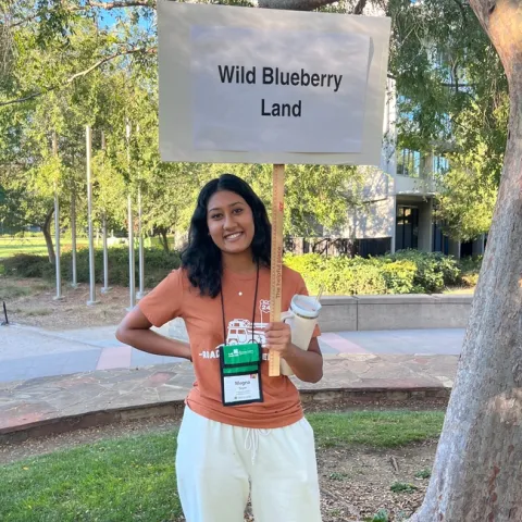 Megna holding sign saying "Wild Blueberry Land"